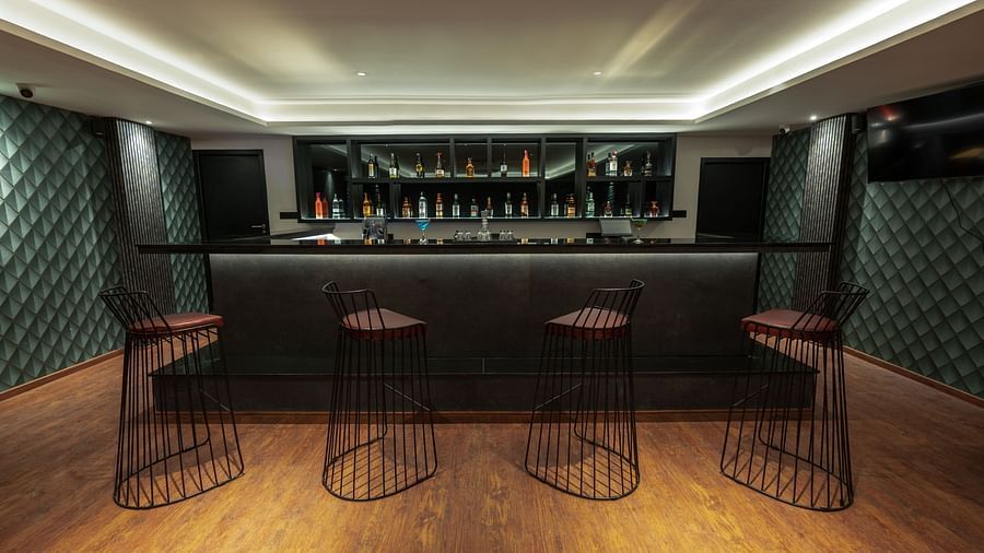 image of the english club featuring the bar counter lined up with elevated chairs - Darza Resorts