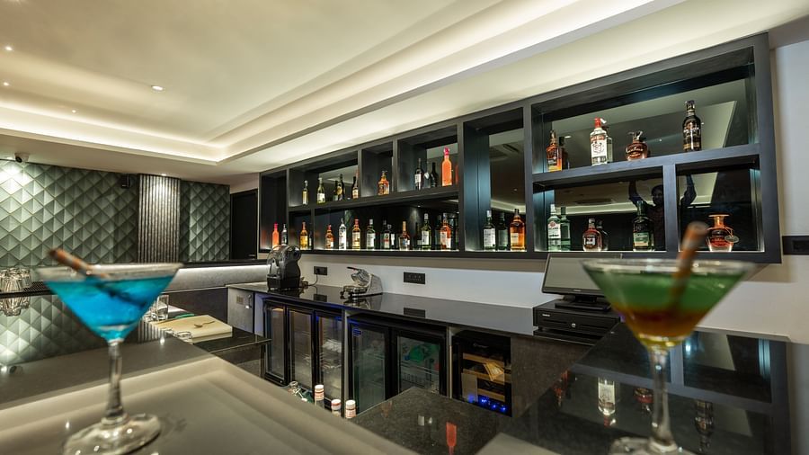 corner view image of the bar at the english club featuring two martini classes with cocktails - Darza Resorts
