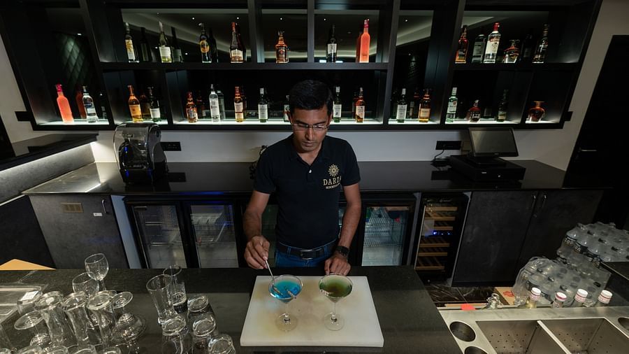 image of a bartender making cocktails behind the bar of the english club - Darza Resorts