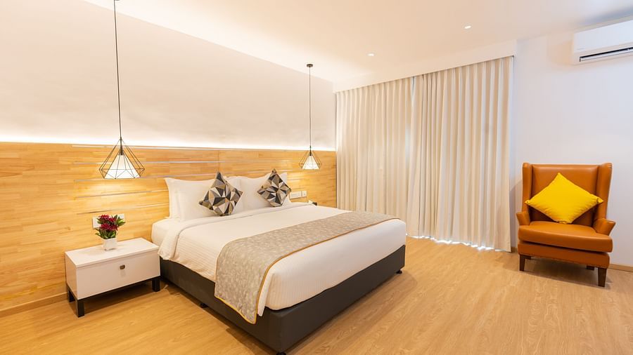 image featuring a plush double bed along with an arm chair at one corner of the room in the garden view room - Darza Resorts