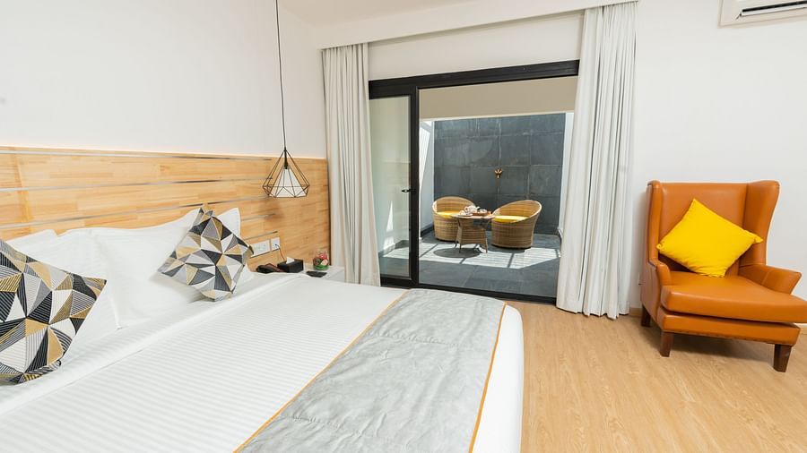 image featuring a double bed along with huge french windows overlooking the outdoor seating area at the garden room - Darza Resorts