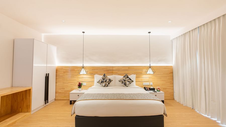 front view image of the garden view room that highlights a double bed along with two lights hanging from the ceiling above the bed side tables - Darza Resorts