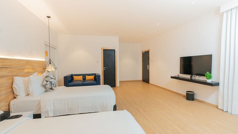 side view image of the double bed along with a wall mounted television placed right opposite to it in a garden room - Darza Resorts