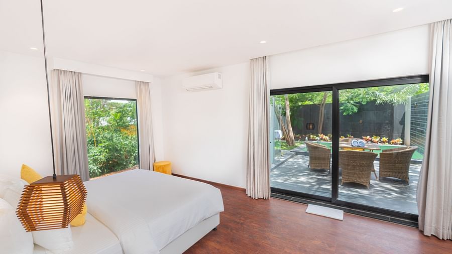 image of a bedroom featuring huge french windows overseeing the outdoor seating area at the family villa two bedroom - Darza Resorts