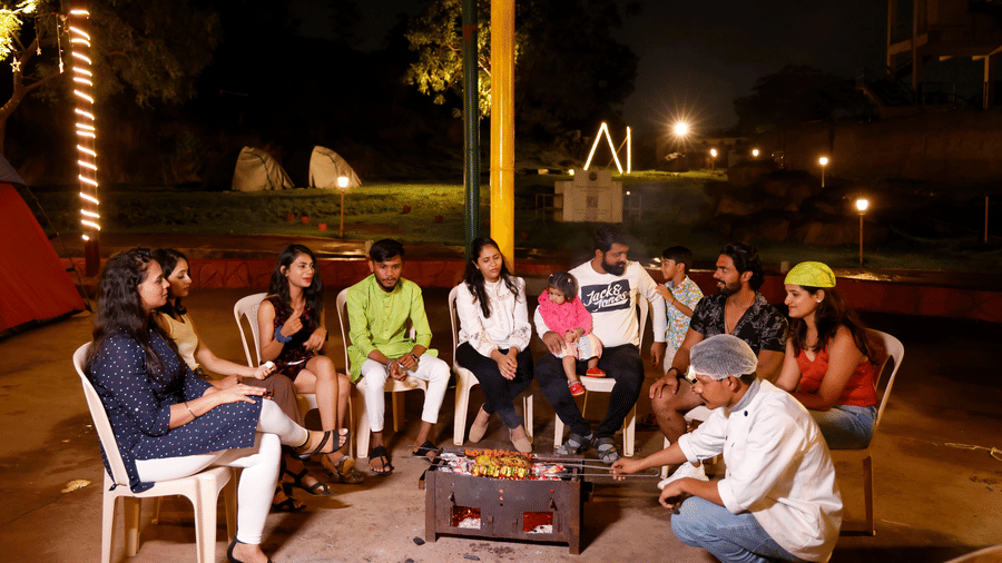 A group of people enjoying a bonfire in Pune at a camping site in the evening at Diamond Parks, Pune