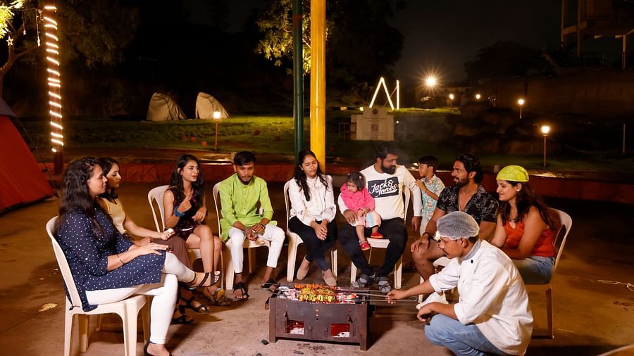 Group of friends enjoying a bonfire at a camping site in the evening | Diamond Parks, Pune