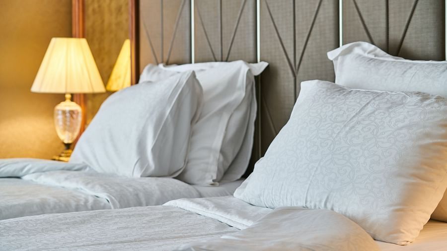 A plush bed with textured grey bedding, decorative pillows and elegant bedside lamps in a luxury setting.