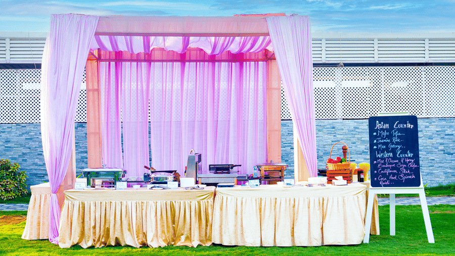 Outdoor buffet counter decorated with lavender drapes set on a green lawn - Grande Bay Resort & Spa, Mamallapuram
