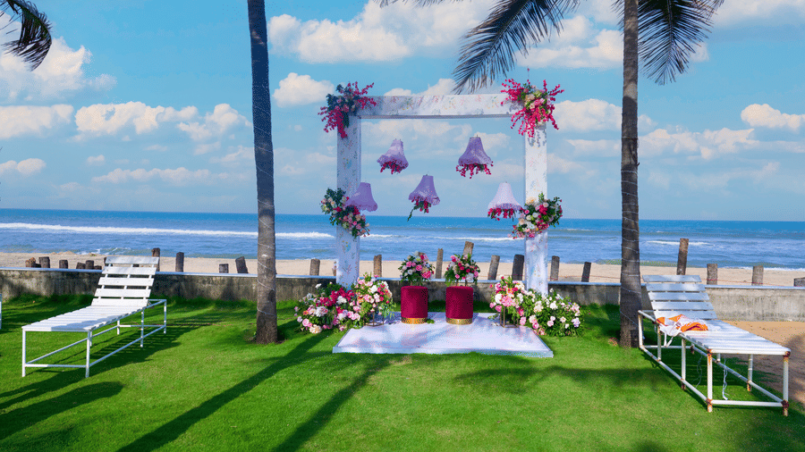 Outdoor garden seating arrangement with floral backdrop overlooking the sea - Grande Bay Resort & Spa, Mamallapuram