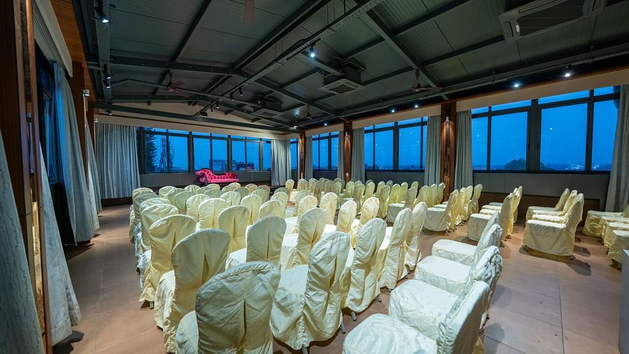 Hari Govinda's Express, Vijayanagar, features a banquet area with a central aisle, neatly arranged chairs, and a stage with a cushioned sofa.