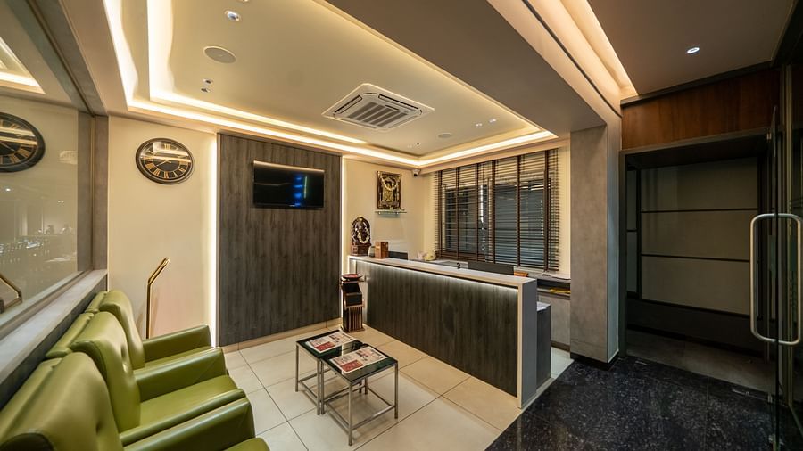 Hari Govinda's Express, Vijayanagar, welcomes guests with a large desk, cushioned sofa, glass table, and warm lighting.