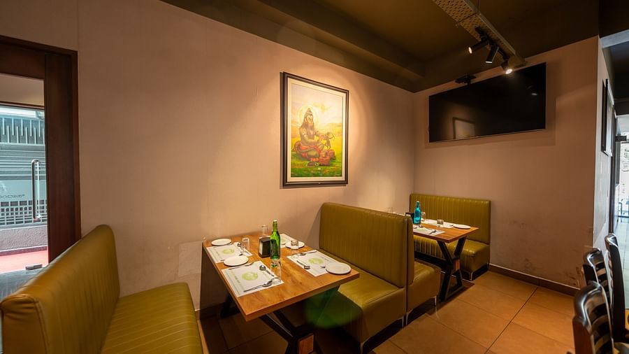 Image of a dining section with seating area and a photo frame mounted on the wall at Hari Govindas, Siddappa Square.
