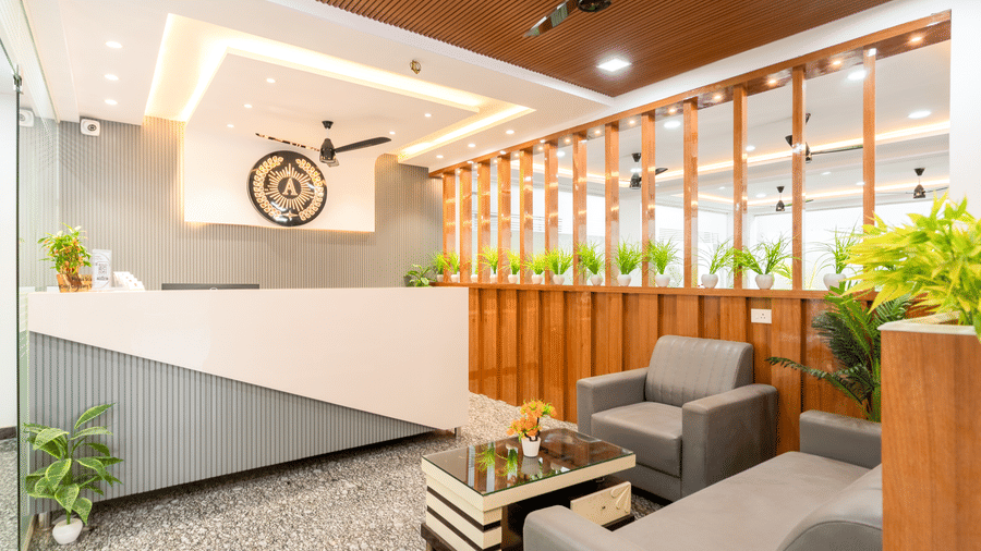 A lobby at Hotel Aurora Bliss, Gachibowli, featuring a large desk, sofas, plants, and a table.