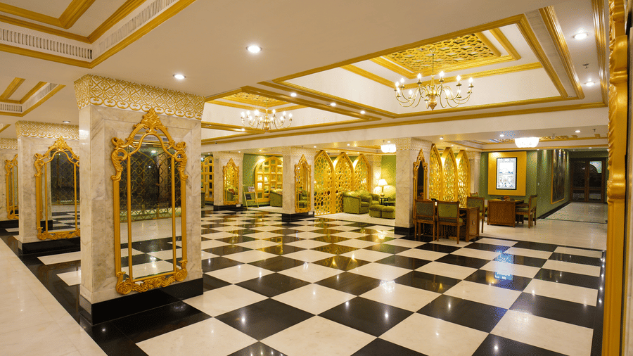 An overview of the Lobby area of Hotel Clarks Shiraz, Agra, one of the best Family Hotels in Agra near Taj Mahal, with checkered tiles and gold chandeliers 
