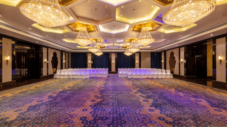 Symmetric view of the large hall featuring multiple tables and chairs, dominated by the elaborate honeycomb chandeliers at Hotel Hukam's Lalit Mahal.