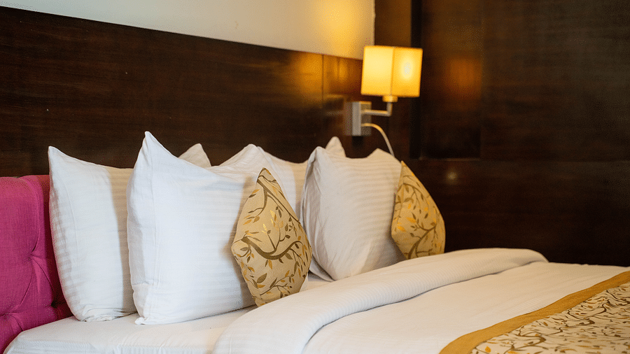 A luxurious hotel bed with plush pillows, gold-accented linens, and ambient lighting - Hotel Udai Median, Udaipur.