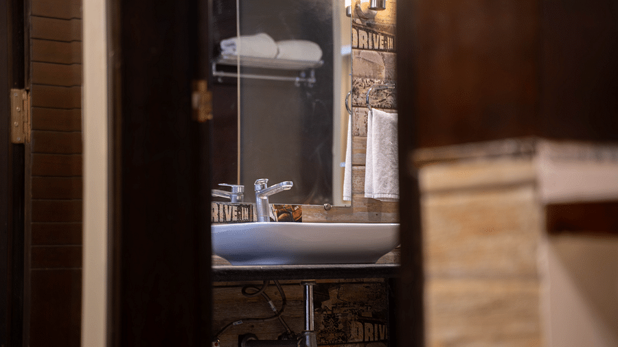 A bathroom view with a sleek vanity mirror, glass shower, and warm lighting - Hotel Udai Median, Udaipur.