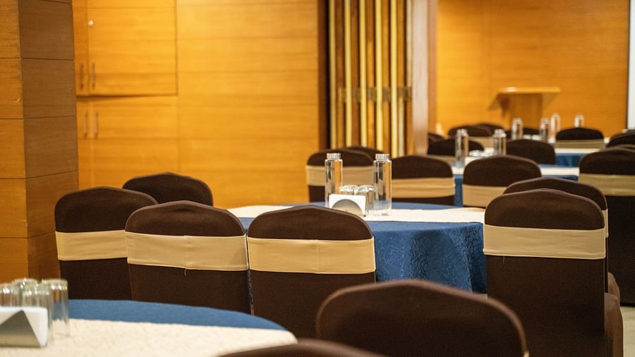 A banquet hall with round tables covered in blue tablecloths and brown chairs - Hotel Udai Median, Udaipur.