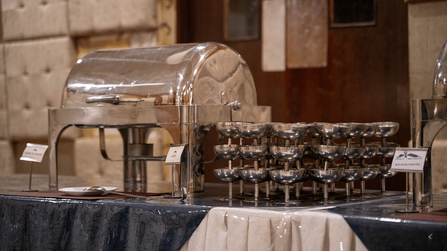 A buffet station with a stainless-steel chafing dish and neatly arranged serving glasses - Hotel Udai Median, Udaipur.
