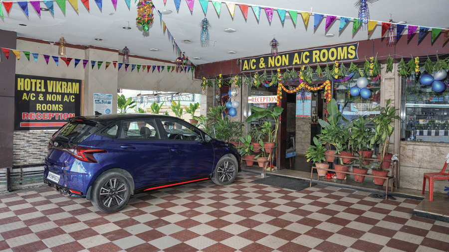 The indoor parking and entrance area of Hotel Vikram, decorated with colourful flags and featuring a parked car.