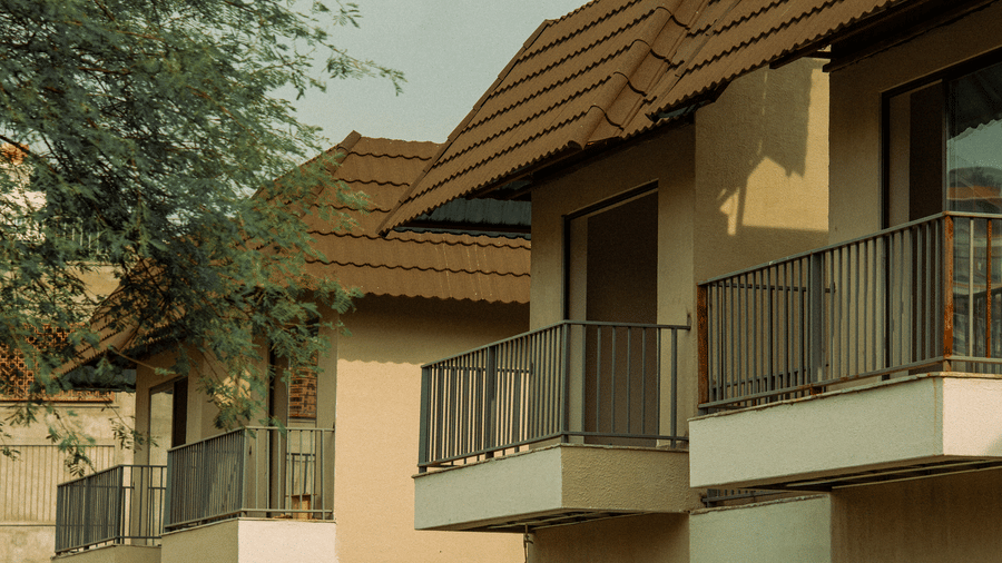 2-storey tan buildings feature brown tiled roofs and black metal railings on several small rectangular balconies at Jivana Wellness Retreat, Bhopal.