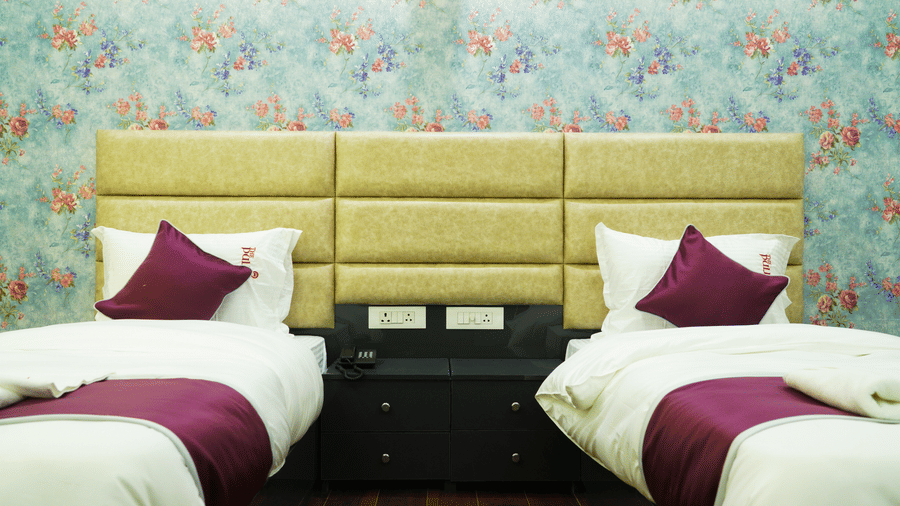 Bedroom of Lime Tree Hotel, Pulkit featuring twin beds, floral wallpaper, and maroon cushions.