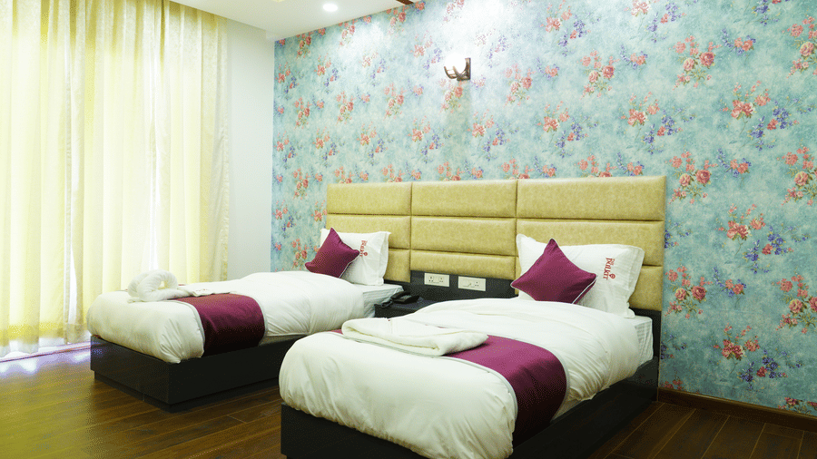 Bedroom of Lime Tree Hotel, Pulkit featuring twin beds, floral wallpaper, and yellow curtains.