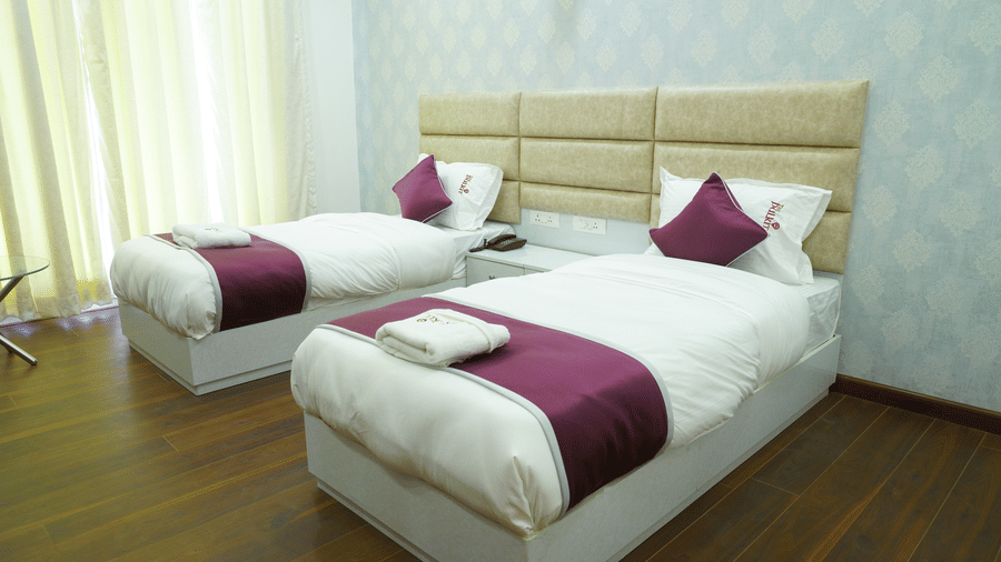 Bedroom of Lime Tree Hotel, Pulkit featuring twin beds, a beige headboard, and maroon cushions.