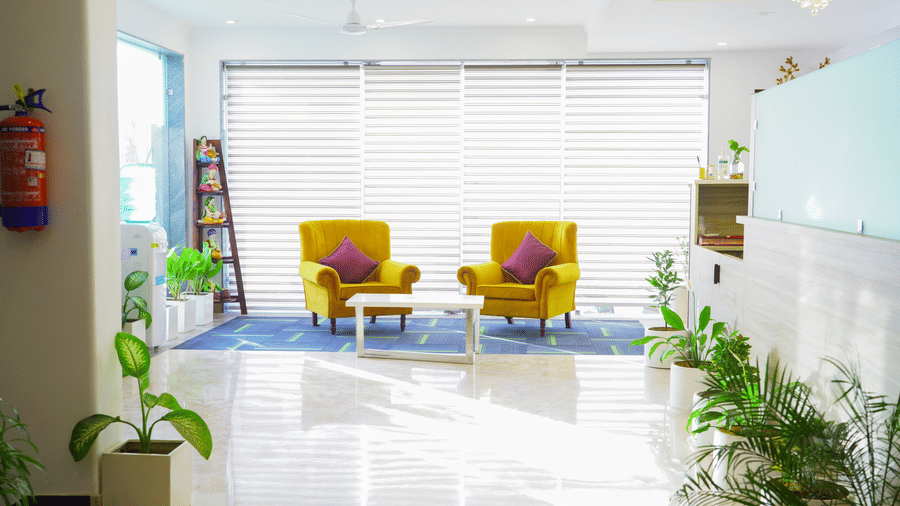 Lobby of Lime Tree Hotel, Pulkit featuring yellow armchairs, blinds, and potted plants.