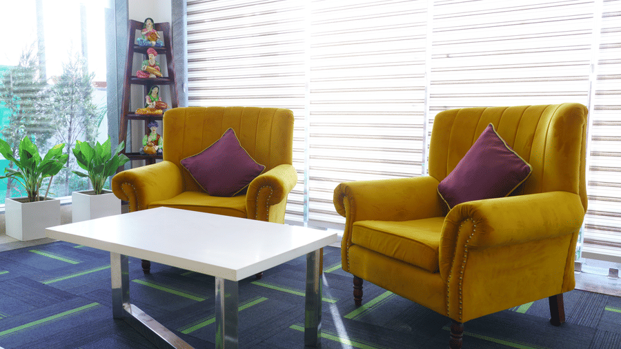 Lounge area of Lime Tree Hotel, Pulkit featuring yellow armchairs, a white coffee table, and shutter panelling.