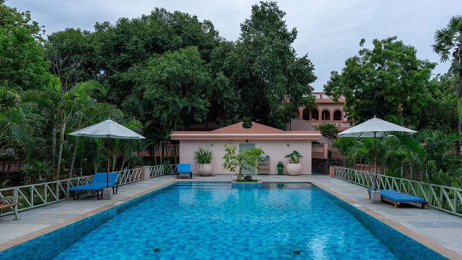 Swimming pool in front  of a property with lawn chairs