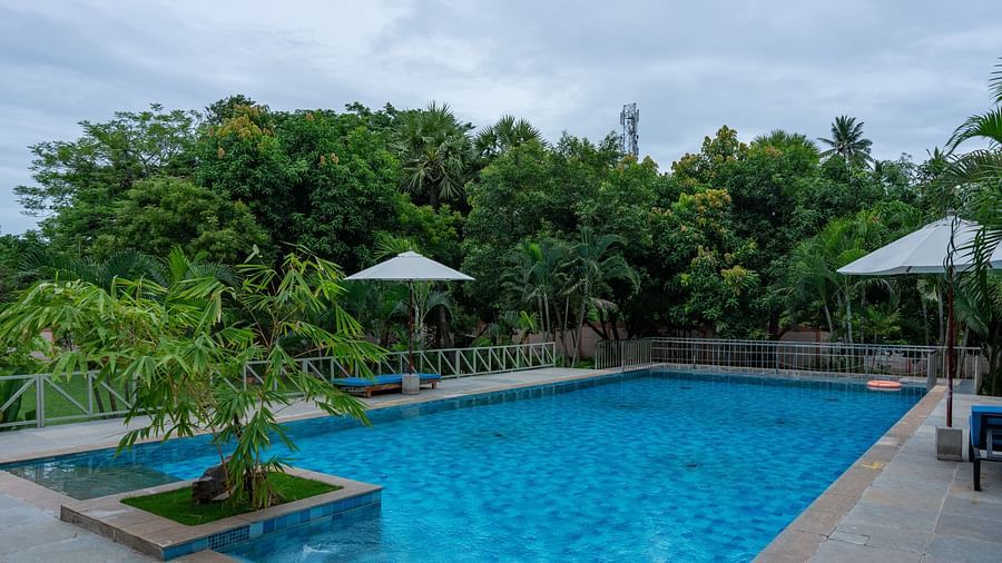 Side view of  swimming pool in front  of a property with lawn chairs