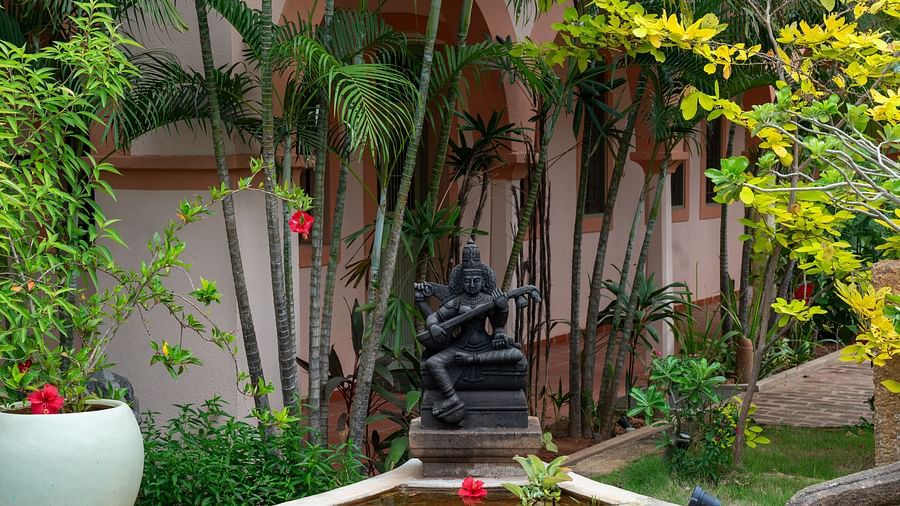 An idol placed in the middle of the  pillar surrounded by trees.