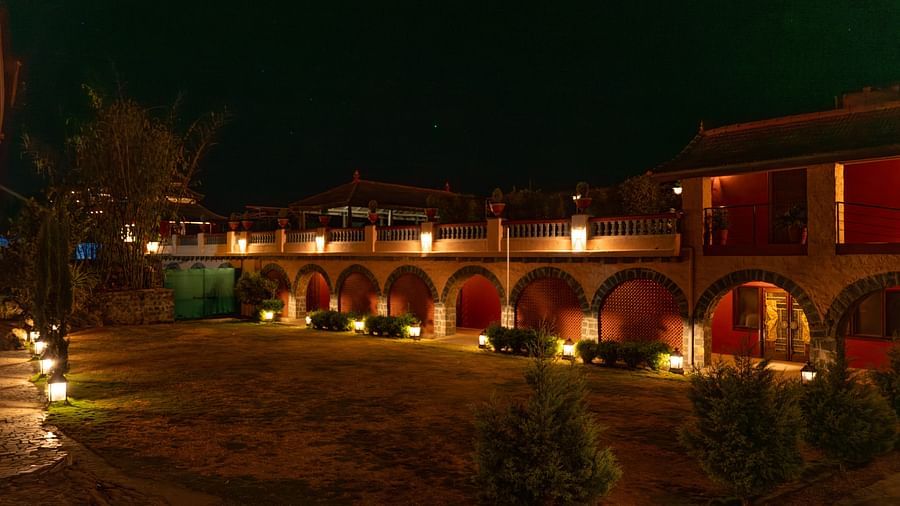 Exterior view of a well-lit building with arches at night, surrounded by a garden.  | Mango Hill, Yercaud