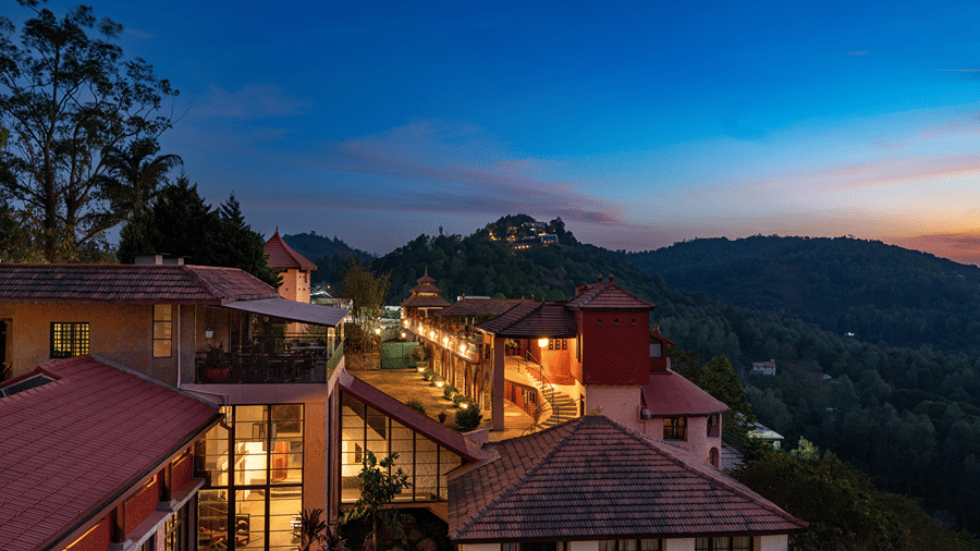 Nighttime view of the brightly-lit resort buildings of Mango Hill, Yercaud, with forested hills in the background.