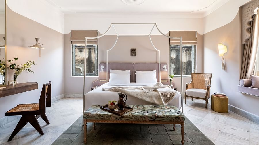 a double bed with a small seating area at the base of the bed inside one of the rooms - Manuscript - Jhilwara Haveli, Udaipur