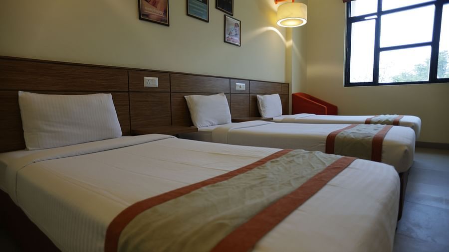 a close up shot of a single bed with the other two beds placed right beside it - Max Hotel Jabalpur