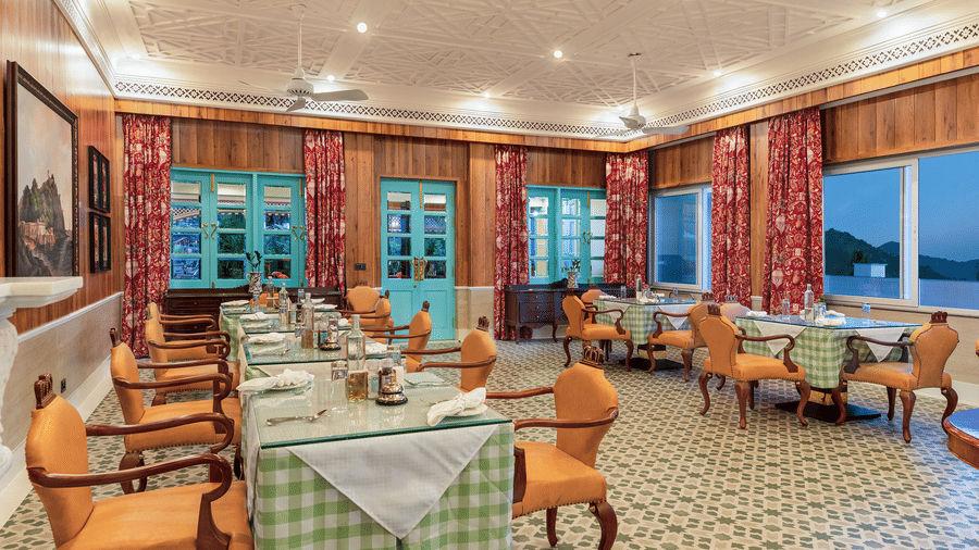 Warmly lit restaurant area with patterned floor tiles and tables at Mayfair Manor, Jungpana.