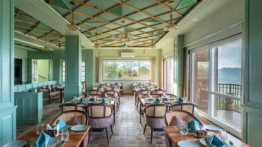 an image of a dining space filled with natural light, chairs and tables are placed with cutlery and hand towels at Mountoria Retreat, Naukuchiatal