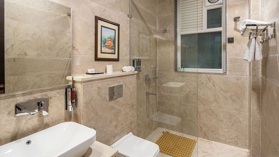 an image of a bathroom with a mirror on the wall, a sink and faucet below it, a shower screen and shower, and other toiletries at Mountoria Retreat, Naukuchiatal