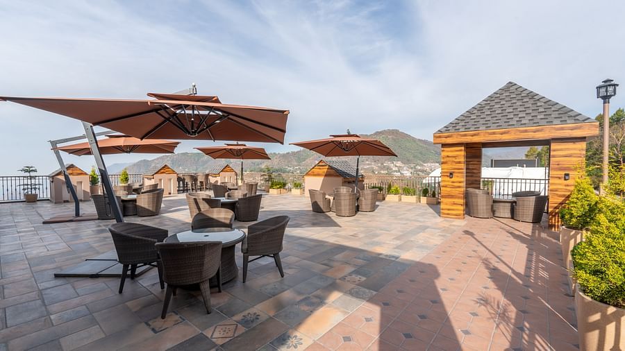 an image of outdoor dining space, each dining table and chair set is segregated and has a roof on top at Mountoria Retreat, Naukuchiatal