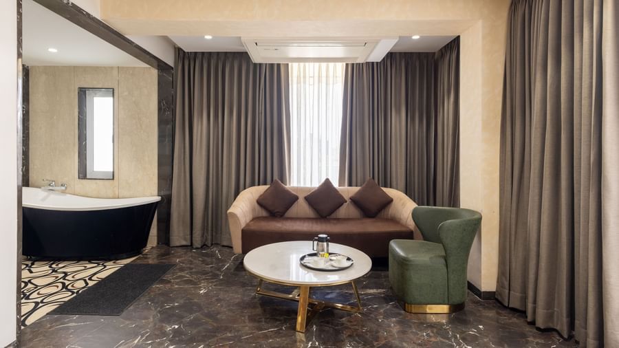 Bathroom and living area of Pravasa Stay Vijay Nagar, Indore, with the bathtub, and the multi-seating sofa seen.