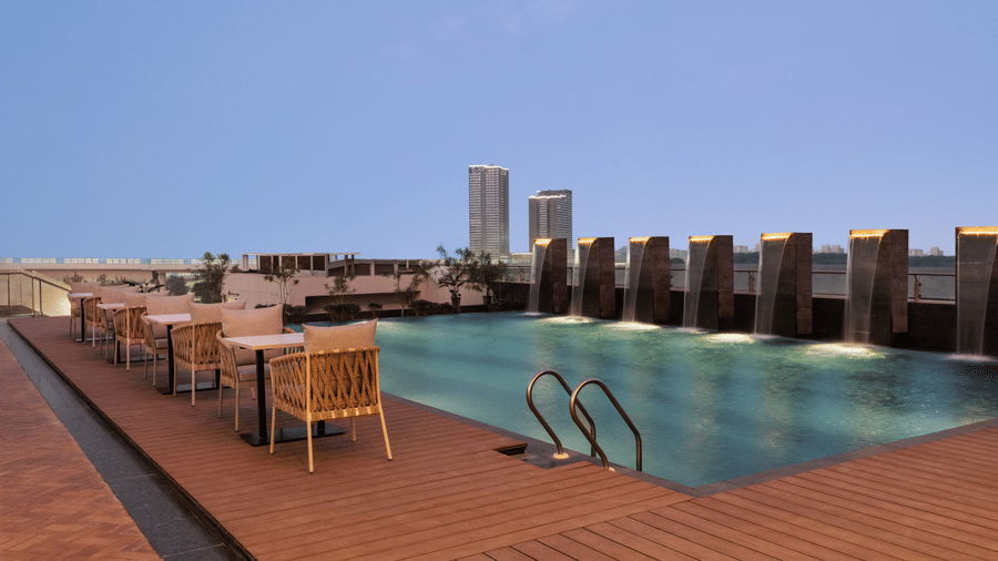 Rooftop swimming pool with loungers and seating at Ramada Encore by Wyndham Gurugram Dwarka Expressway, offering a relaxing outdoor space for guests.