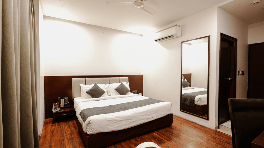 Executive Room at TGI Apple Inn, Ajmer Road, Jaipur featuring a bed, mirror on the wall, air conditioner, and doorway.