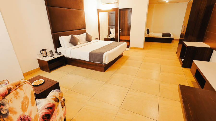 Elegant guest room with comfortable seating, modern furnishings and ample space at TGI Apple Inn, Ajmer Road, Jaipur.