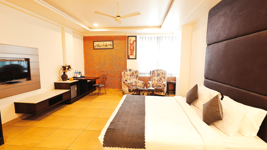 Well-appointed room featuring a king-size bed, lounge seating and tasteful décor at TGI Apple Inn, Ajmer Road, Jaipur.