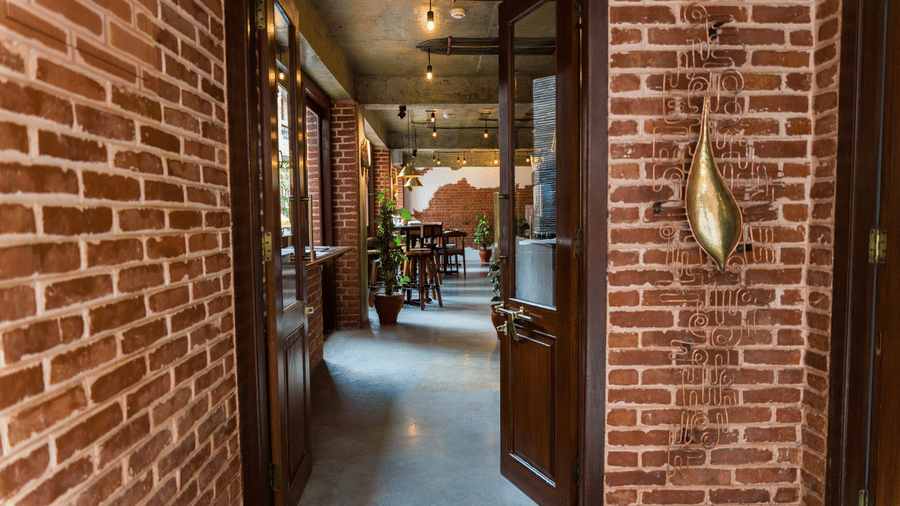 Brick-walled hallway with wooden doors and warm ambient lighting inside The Nanee, Bhaktapur, Nepal.