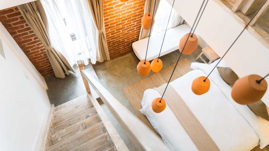 An aerial shot of the deluxe loft room with a staircase and chandelier hanging above it - The Nanee