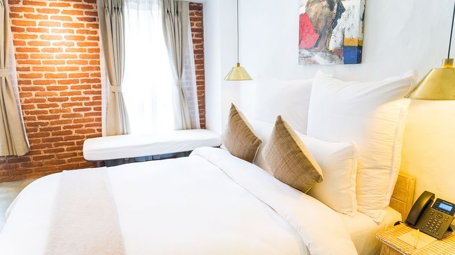 The deluxe loft room with a bed, bed side table, with a telephone places on it, and lamps - The Nanee