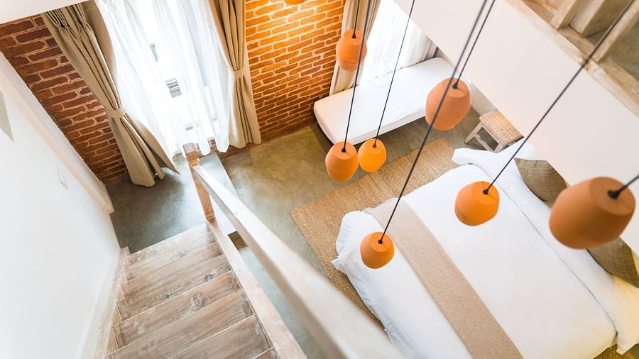 An aerial shot of the deluxe loft room with a staircase and chandelier hanging above it - The Nanee